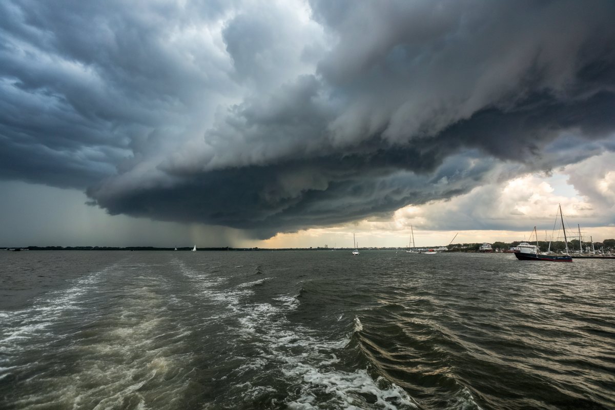 Dark storm clouds rolling in over a wide harbor with choppy gray water